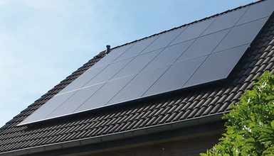 Hausdach mit schwarzen Ziegeln und Solarzellen