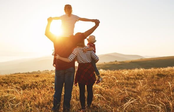 Familie schaut harmonisch in den Sonnenuntergang