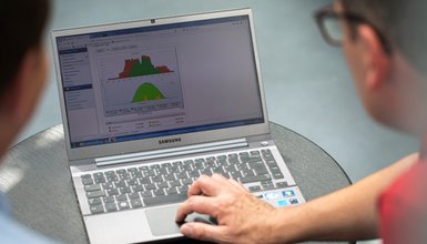 Zwei Menschen mit einem Laptop auf dem Diagramme zu sehen sind