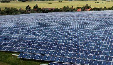 Solarpark aus der Vogelperspektive, im Hintergrund grüne Felder und Bäume