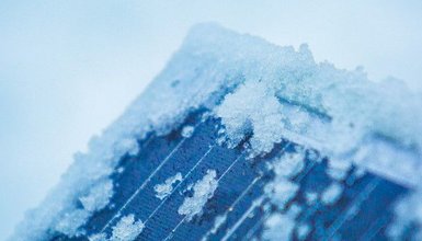 Nahaufnahme einer Ecke eines Solarmoduls stellenweise bedeckt mit Schnee