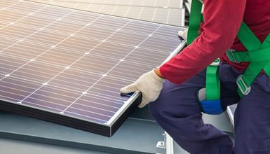 Nahaufnahme Solarmodul das von einer Person in rotem Pullover angebracht wird