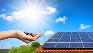 Solaranlage auf Dach bei schönem Wetter. Im Vordergrund Hand mit Geld